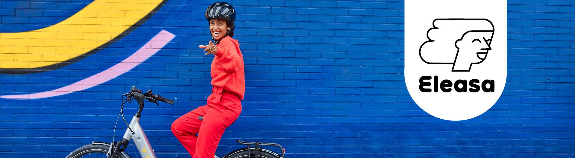 Eine Frau sitzt auf ihrem E-Bike vor einer blauen Wand. Neben ihr ist das Eleasa-Logo zu sehen.