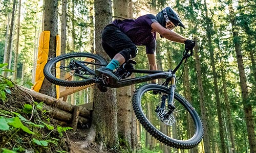 Radfahrer springt im Wald mit einem Fully-Mountainbike.