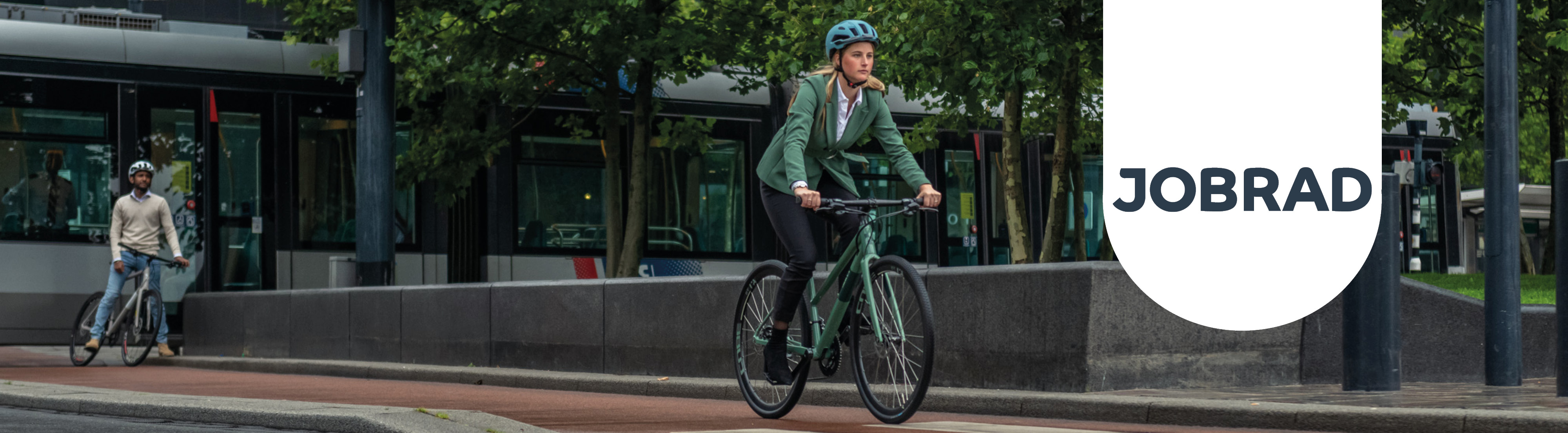 Ein Mann steht mit seinem Fahrrad neben einer Straßenbahn. Eine Frau fährt mit ihrem grünen Fahrrad den Fahrradweg entlang. Neben ihr ist das Jobrad-Logo zu sehen.